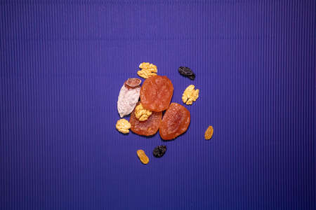 Dried fruit and walnuts on a purple background