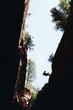 A silhouette of a mountain climber climbing a rock during daytime at  Zion National Park, USA