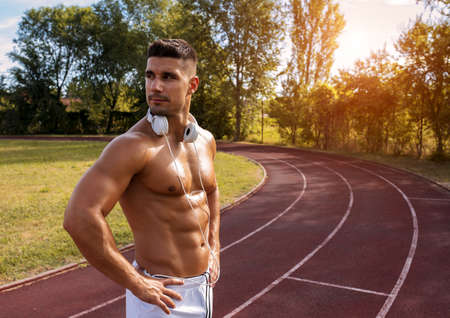 A young shirtless Caucasian male standing in the park at daytimeの写真素材