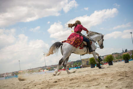 A close up shot of a horse rider dressed in traditional red clothes riding a horseの写真素材
