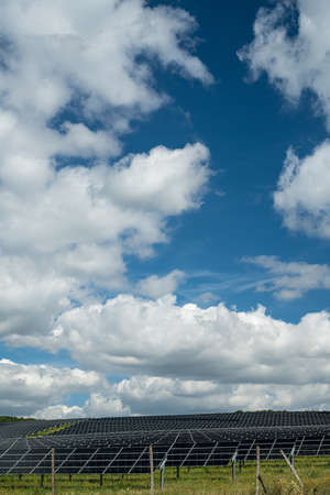 A vertical shot of solar panels in the field in the countryside under the cloudy sky