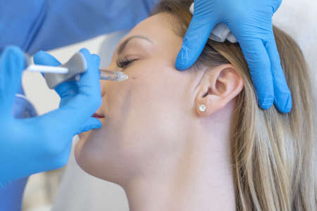 A closeup of a doctor performing cosmetic surgery on a young female under the lights
