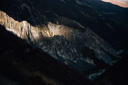 An aerial shot of a river going through the mountains with the sun shining through the clouds