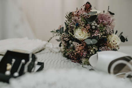 A selective focus shot of the wedding beautiful bouquet with white elegant shoesの写真素材