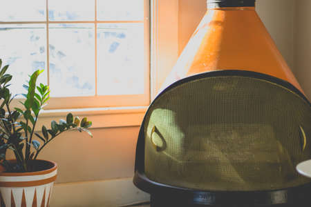 An orange modern fireplace in a minimalistic house with large glass window and a plantの写真素材