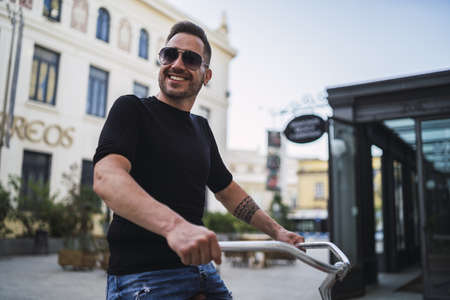 A young Caucasian male riding a bicycle on the street at daytimeの写真素材