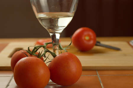 A closeup shot of tomatoes on a vine and a glass of white wineの写真素材