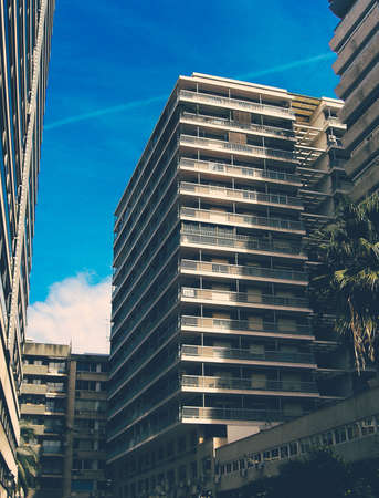 A vertical shot of a tall apartment building with balconies on a sunny day