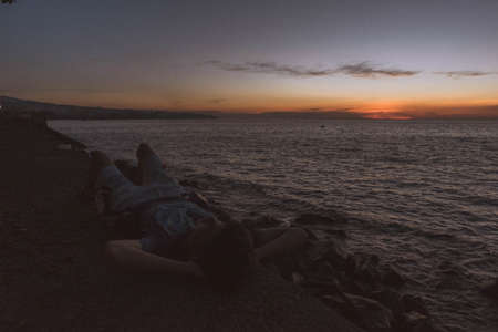 A male laying and relaxing on the rocks at the coast of the seaの写真素材