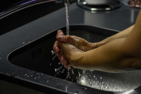 A shallow focus shot of a person washing hands in the sink
