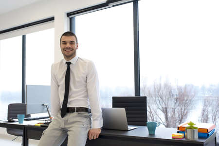 A young male entrepreneur leaning on his desk at the office