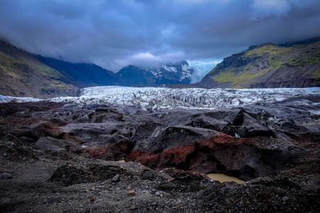 A wide shot of mountains surrounded by white and gray stones under cloudy skyの写真素材