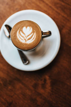 A beautifully made cappuccino served with flower art on the foam shot from an overhead viewの写真素材