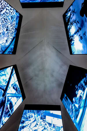 A vertical shot of tv screen with different pictures and a gray ceiling in the background