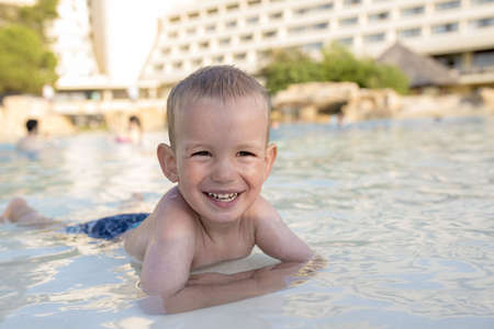 A Caucasian young boy swimming in the pool and happily smilingの写真素材