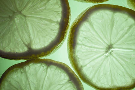 An overhead shot of sliced lemons on a surface under the green light