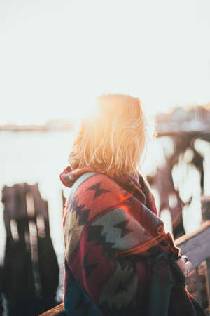 A vertical shot of a woman covered in a multicolored Aztec blanket