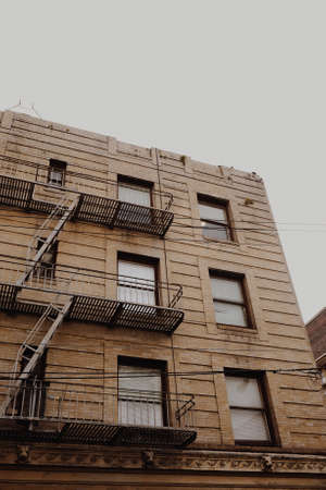 A low angle shot of apartment buildings with emergency staircase on the side near windows