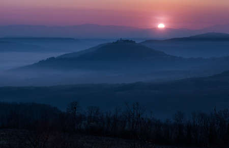 A beautiful scenery of a valley with high mountains enveloped in fog under the breathtaking sunset...