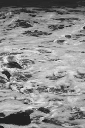 Black and white shot of river flowing and splashing with foam