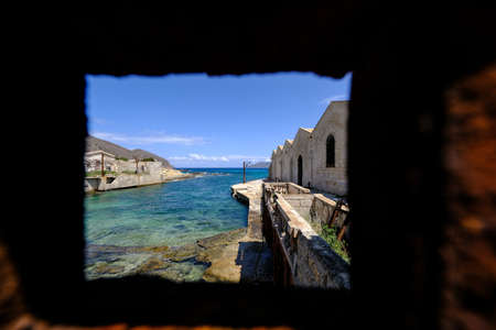 A beautiful shot of  buildings near the sea shot from a square hole in a wallの写真素材