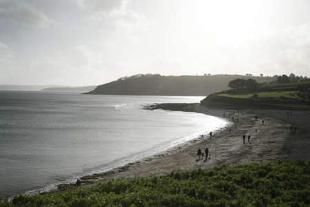 The people walking on the shore of the sea during sunsetの写真素材