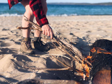 A female lighting stick on fire near a bonfire at the sandy beachの写真素材