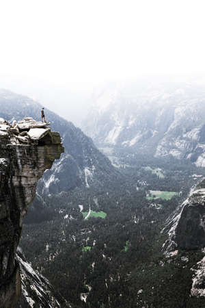 A person standing at the edge of a rocky mountain.