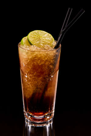 Exotic cocktail drink with lime and straws with glass reflection on black backgroundの写真素材
