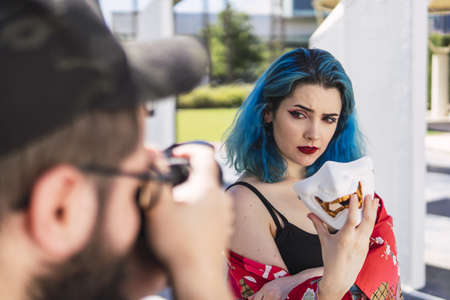 A shallow focus of a young female with blue hair and a scary mask modelling for a photographerの写真素材