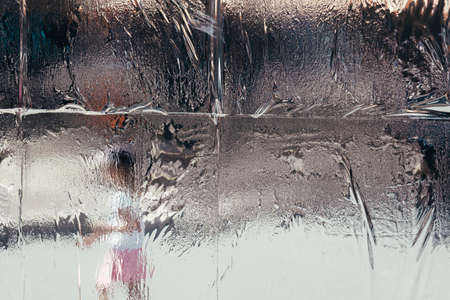 Wet melting frost on the window with a blurry background