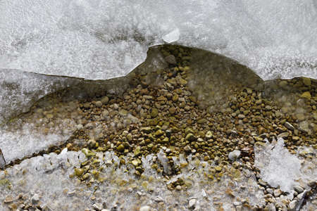 A high angle shot of a frozen beach with lots of small rocks