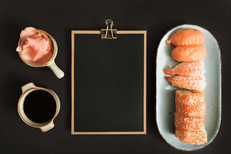 An overhead shot of soy sauce and ginger next to sushis