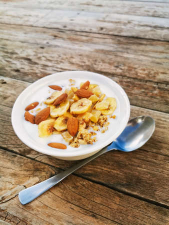 A high angle shot of a yogurt plate with nuts on a wooden table