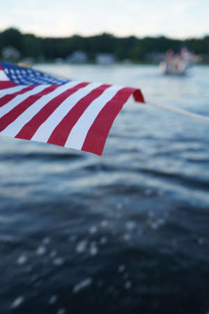 A closeup shot of the American flag waving on a rope with a blurred watery backgroundの写真素材