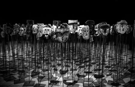 A grayscale shot of masks on metal displays stand with a black background