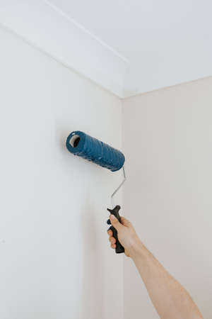 A vertical closeup shot of a person using paint rollers with the color blue