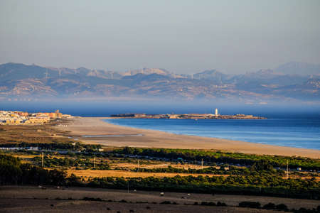 A beautiful shot of shoreline near the trees and mountain in the distanceの写真素材