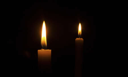 Two burning candles on a black background