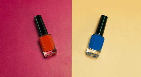 A high angle shot of red and blue nail polishes on a half-split red and yellow surfaceの写真素材