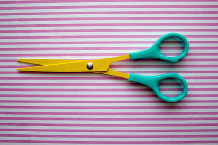 Acloseup shot of scissors on a striped surfaceの写真素材
