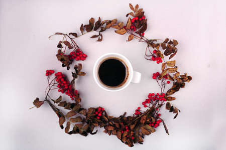 A high angle shot of beautiful flowers around a cup of coffee on a white surface