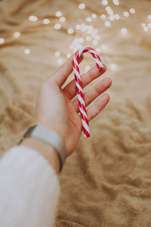 A vertical shot of a female holding a candy cane with a blurred backgroundの写真素材