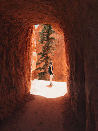 A female hiker standing in front of a Bryce Canyon Tunnel entrance during daytimeの写真素材