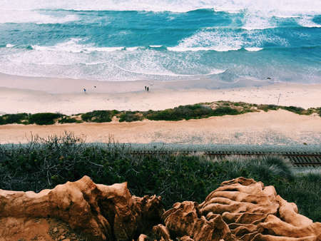 The beautiful scenery of the beach with few people  shot from a higher ground during a sunny dayの写真素材