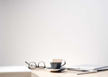 A beautiful shot of optical glasses and a cup on a table with a clean white background - space for text, perfect for article and magazine backgroundsの写真素材