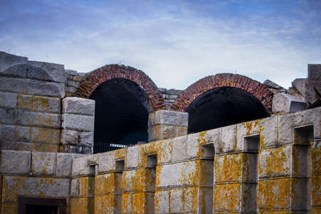 A large stonemade gray structure with yellow mold and arches
