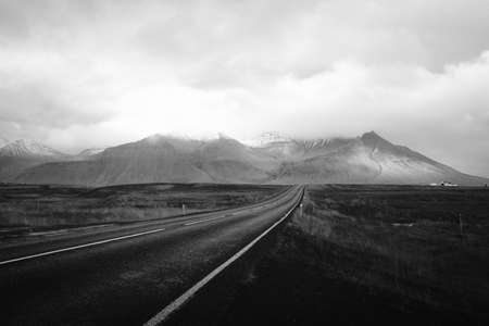 A long across the desert with cloudy hills in the distance shot in black and whiteの写真素材