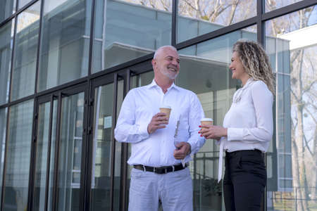 Two colleagues having a nice discussion during the coffee break outside the office buildingの写真素材