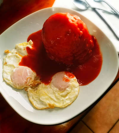 A high angle shot of a plate with fried eggs and tomato sauce dish